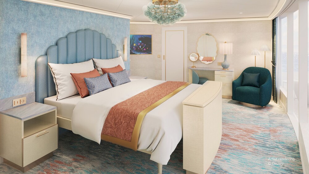 A master bedroom with a vanity and chair inside of The Little Mermaid Royal Suite on the Disney Believe cruise ship