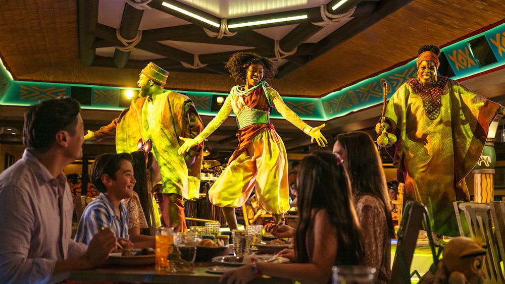 Guests viewing an African dance performance in Pride Lands: Feast of The Lion King on board the Disney Destiny