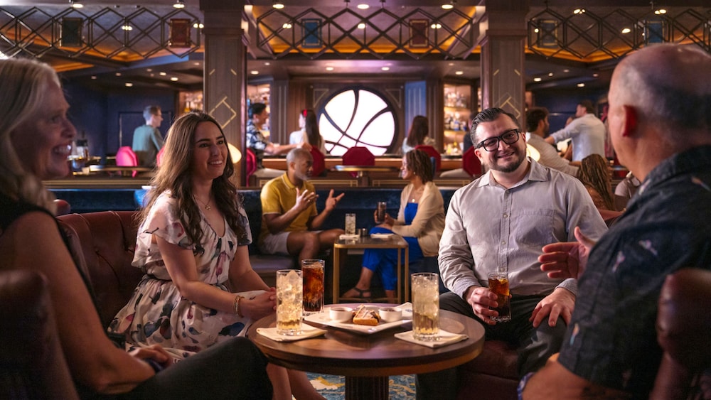 2 couples chatting over beverages in The Sanctum, a Doctor Strange-themed lounge aboard the Disney Destiny