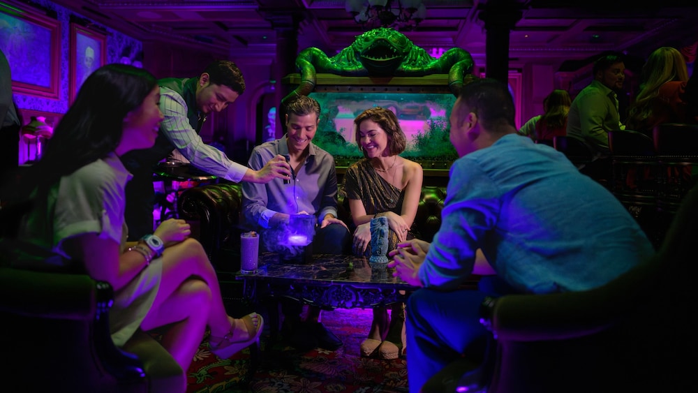 Guests marveling at an eerie cocktail in the Haunted Mansion Parlor aboard the Disney Treasure