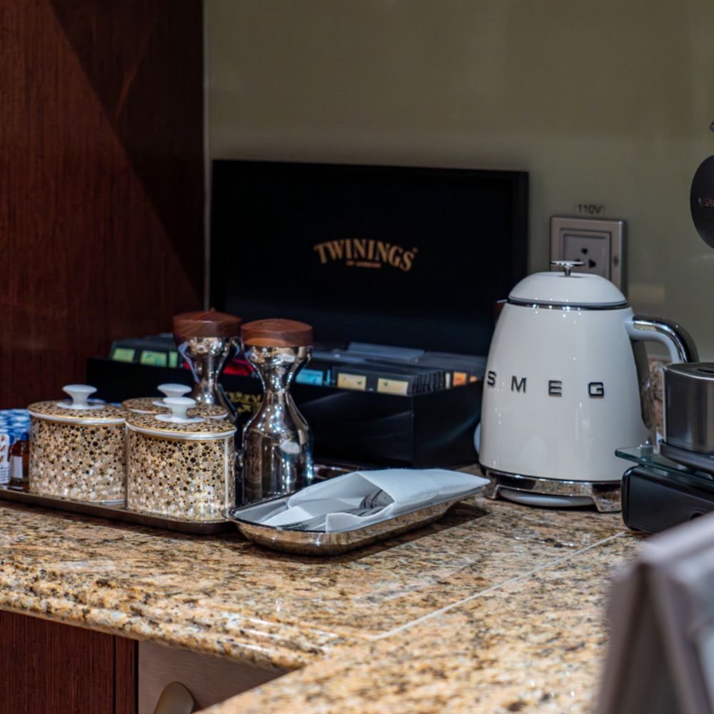 A coffee and tea station with a pot, a coffee maker, a tea box and sweeteners in a Disney Dream Concierge Royal Suite with Verandah