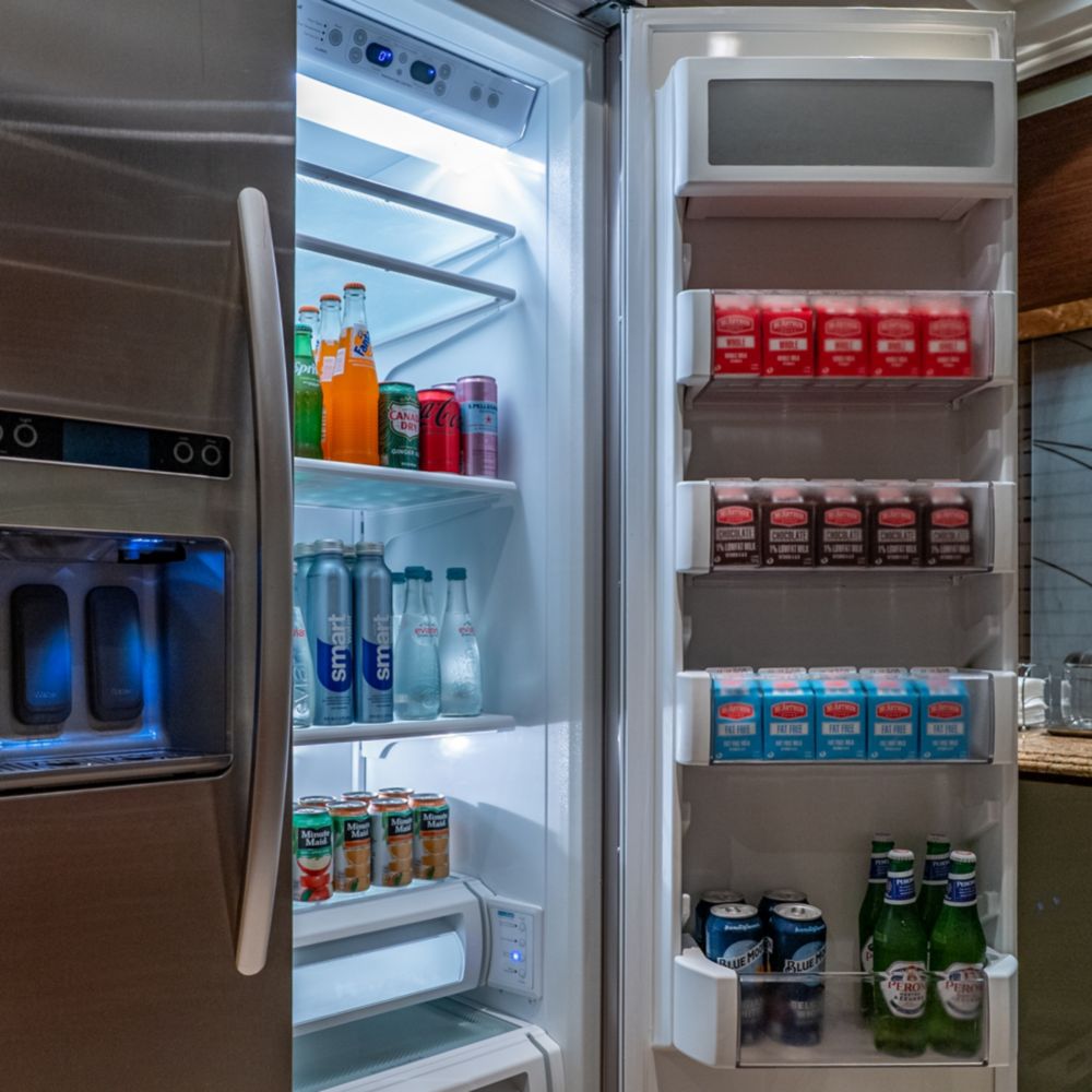 A kitchen with an open refrigerator full of beverages in a Disney Dream Concierge Royal Suite with Verandah