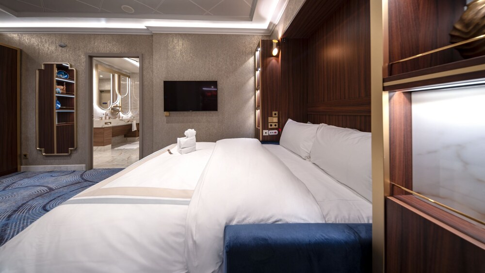 A room with a sofa, a mirror, a tv and a bathroom in a Disney Dream Concierge Dream Tower Suite