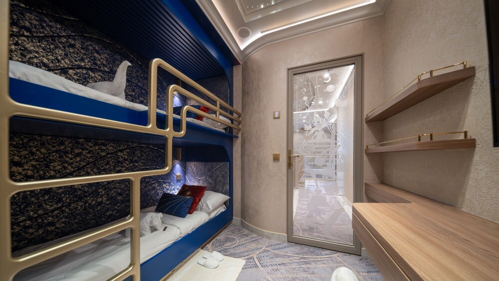 A room with a bunk bed, a desk, cabinets and a bathroom in a Disney Dream Concierge Dream Tower Suite