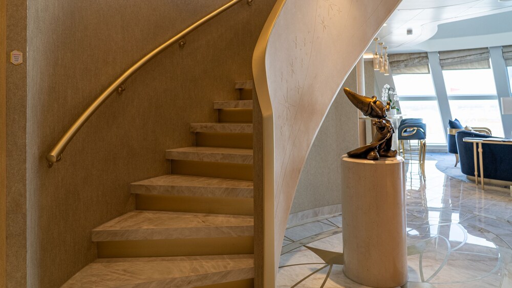 A section of a Disney Dream Concierge Dream Tower Suite with stairs, sofas and chairs