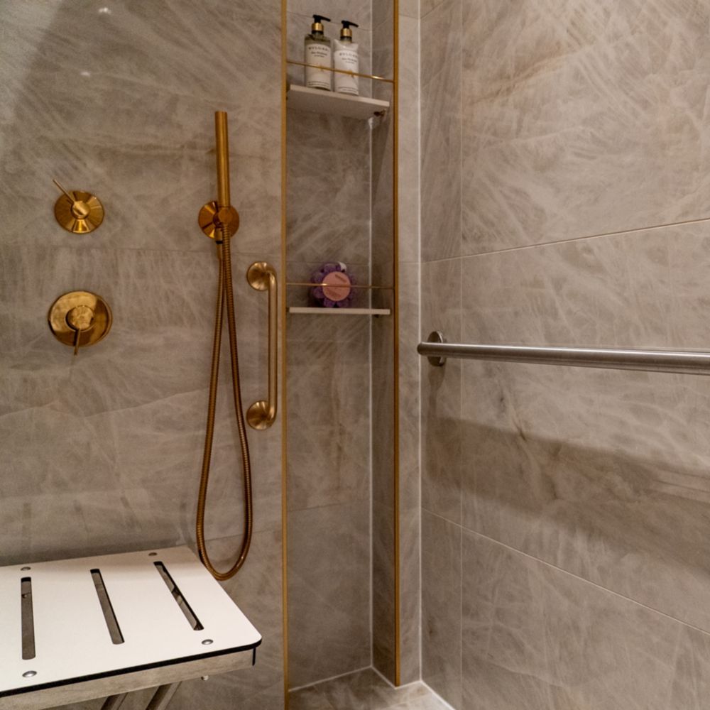 A wheelchair accessible shower with a bench in the bathroom of a Disney Dream Concierge Dream Tower Suite