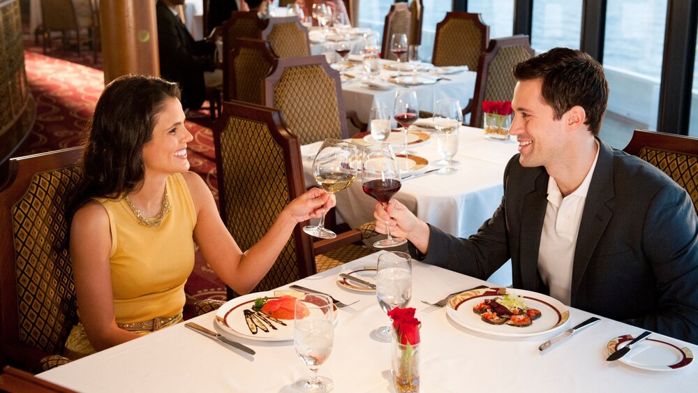 Um casal brindando com taças de vinho enquanto se sentam para jantar no restaurante Palo