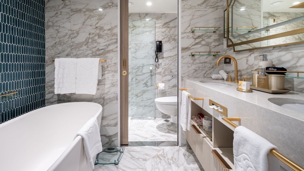 A bathroom with a bathtub, shower, toilet, mirror and 2 sinks in a Disney Magic Concierge 1 Bedroom Suite with Verandah