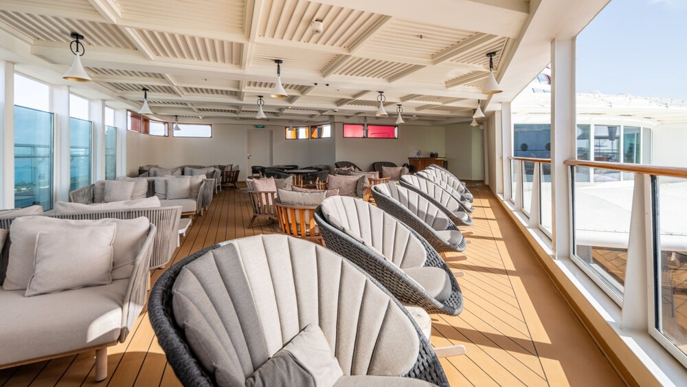 Sofas, chairs and tables on a covered deck in the Disney Magic Concierge Lounge
