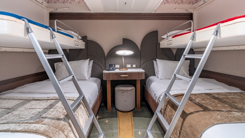 A bedroom with 2 beds, a desk and a stool in a Disney Magic Concierge Royal Suite with Verandah