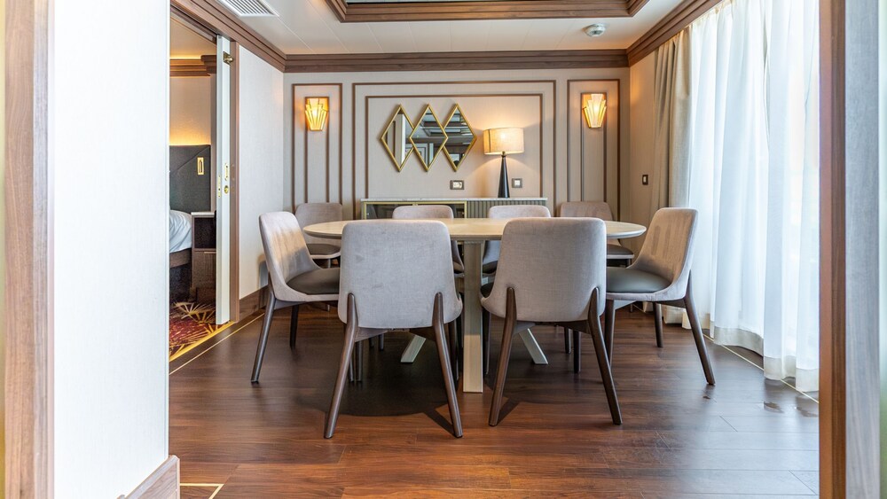 A dining area with a dining table, credenza and 8 chairs in a Disney Magic Concierge Royal Suite with Verandah