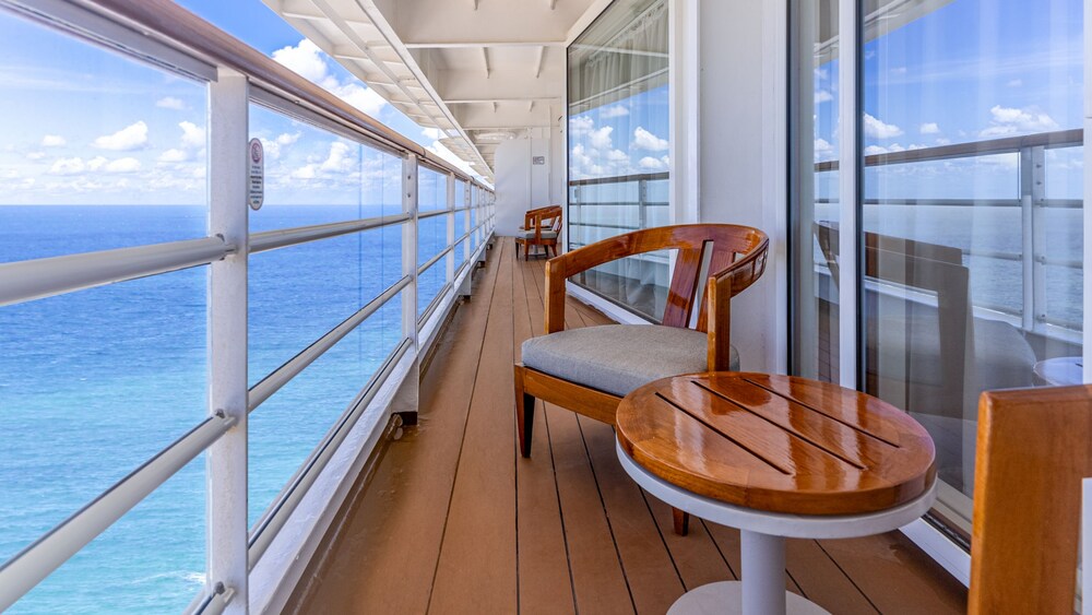 A verandah with 4 chairs and 2 small tables in a Disney Magic Concierge Royal Suite with Verandah