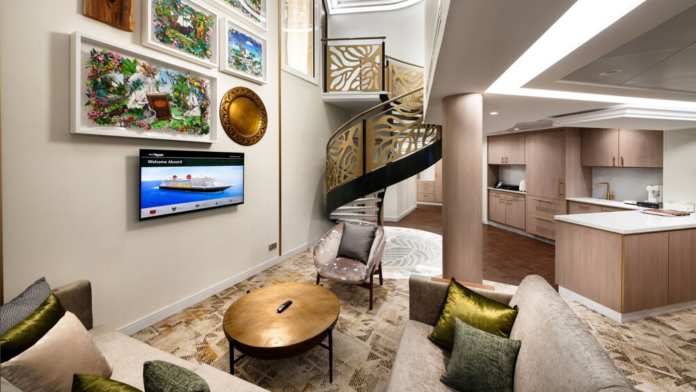 An artist rendering of a Disney Treasure 2 Story Royal Suite with 2 sofas, a chair, a low table, a TV, stairs and a kitchen