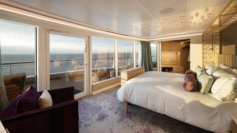 An artist rendering of a Disney Treasure 2 Story Royal Suite with Verandah Stateroom with a sofa, a cabinet, a closet, a bed and a verandah with an ocean view 