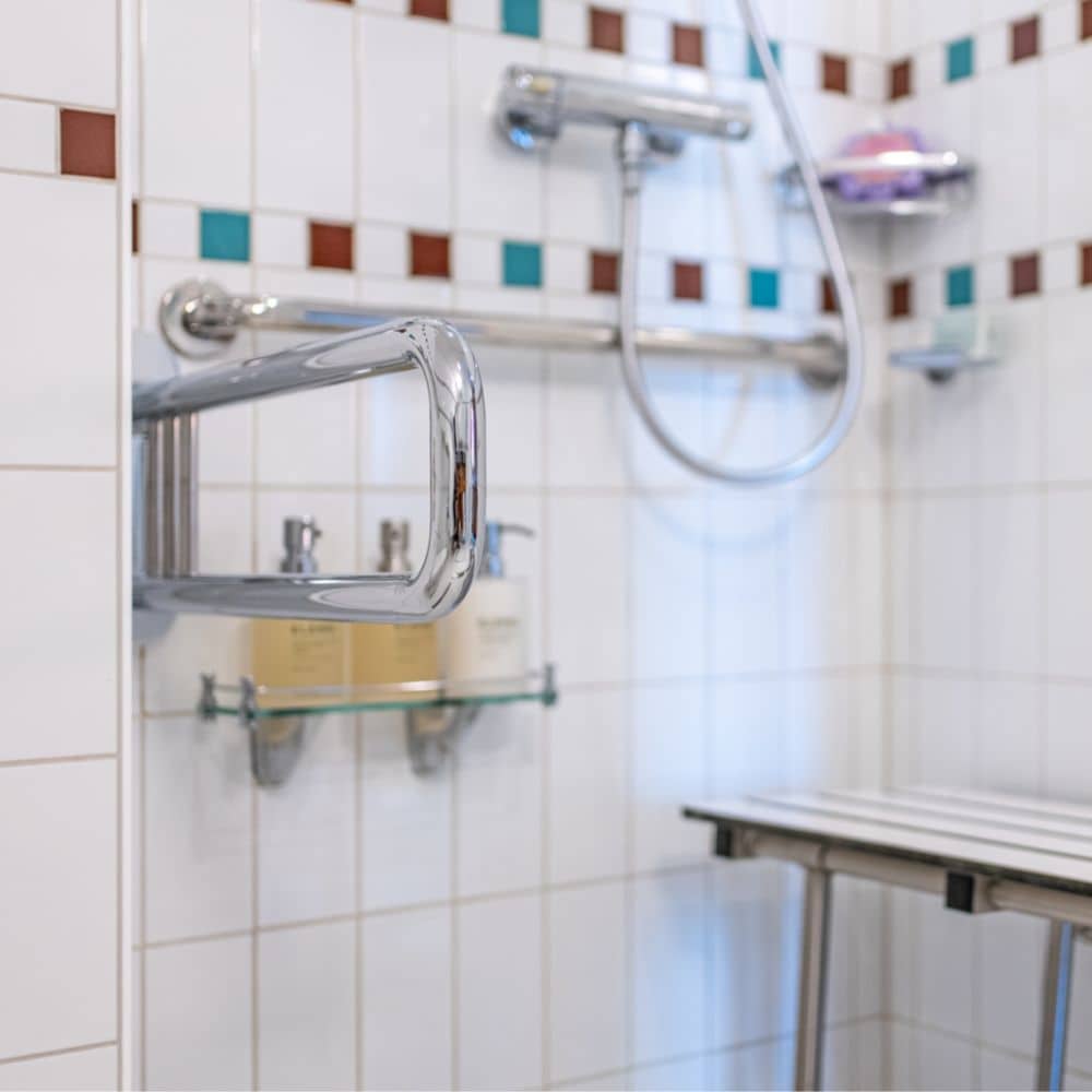 A wheelchair accessible bathroom with a shower and grab bars