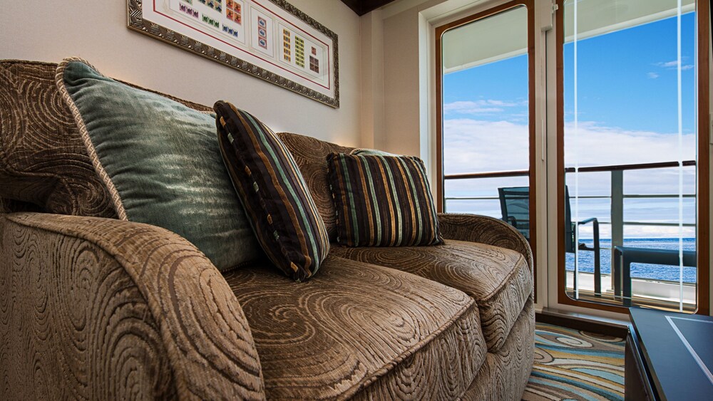 A Disney Cruise Line Concierge Verandah Stateroom with a sleeper sofa and a verandah with an ocean view
