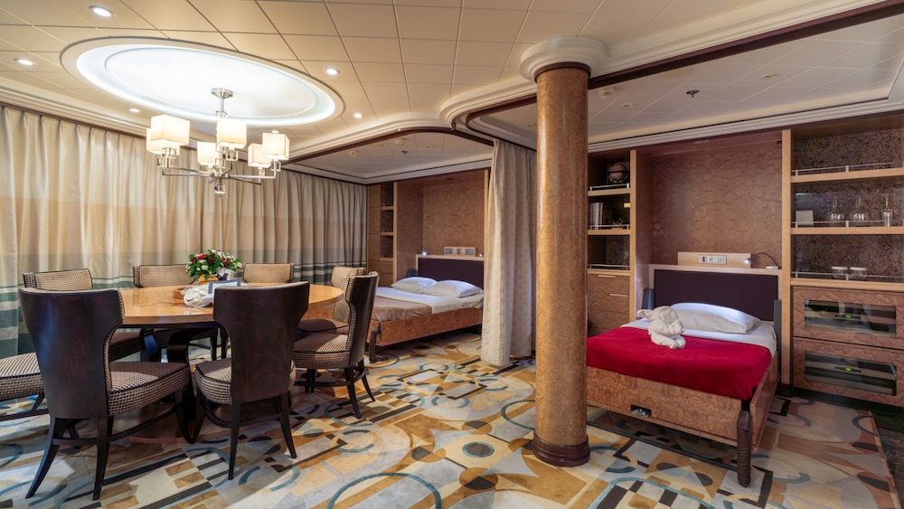 A Disney Cruise Line Concierge Royal Suite with Verandah Stateroom with a dining table, shelves and a sofa