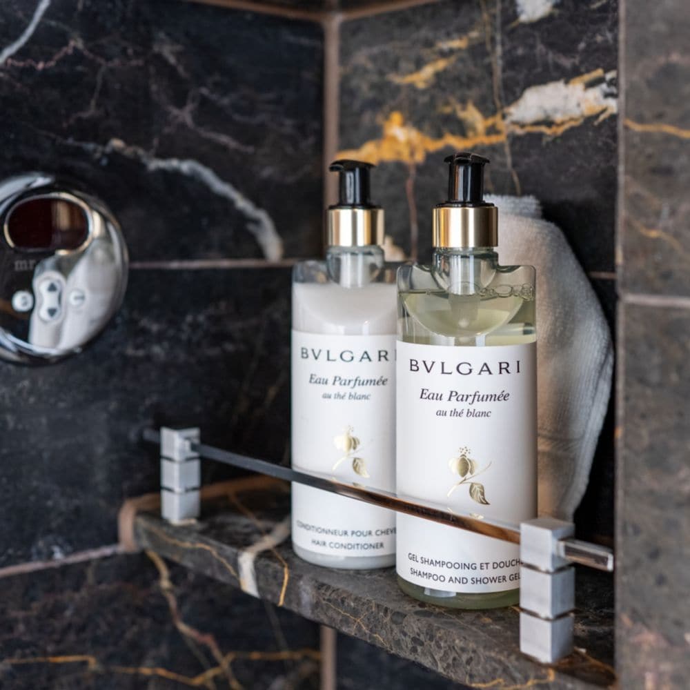 Bulgari conditioner and shampoo and shower gel in a marble shower