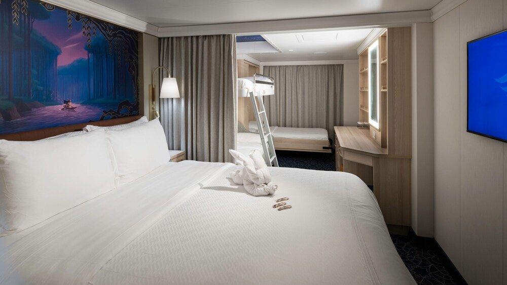 An artist rendering of a Disney Treasure Deluxe Family Oceanview Stateroom with a bed, a bunk bed, a sleeper sofa, a vanity and a TV