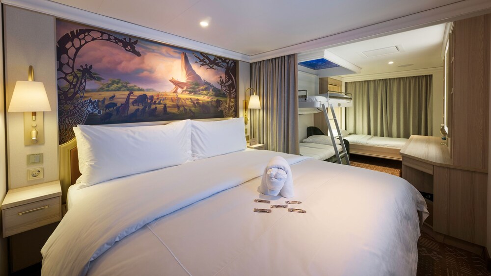 An artist rendering of a Disney Treasure Concierge Family Oceanview with Verandah Stateroom with a bed, a sofa, a vanity and a verandah with an ocean view 