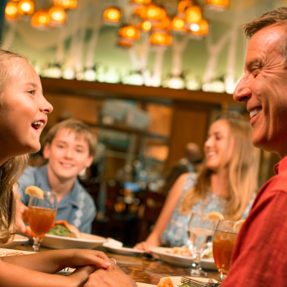 A smiling family of 4 enjoying a meal together at Storytellers Café