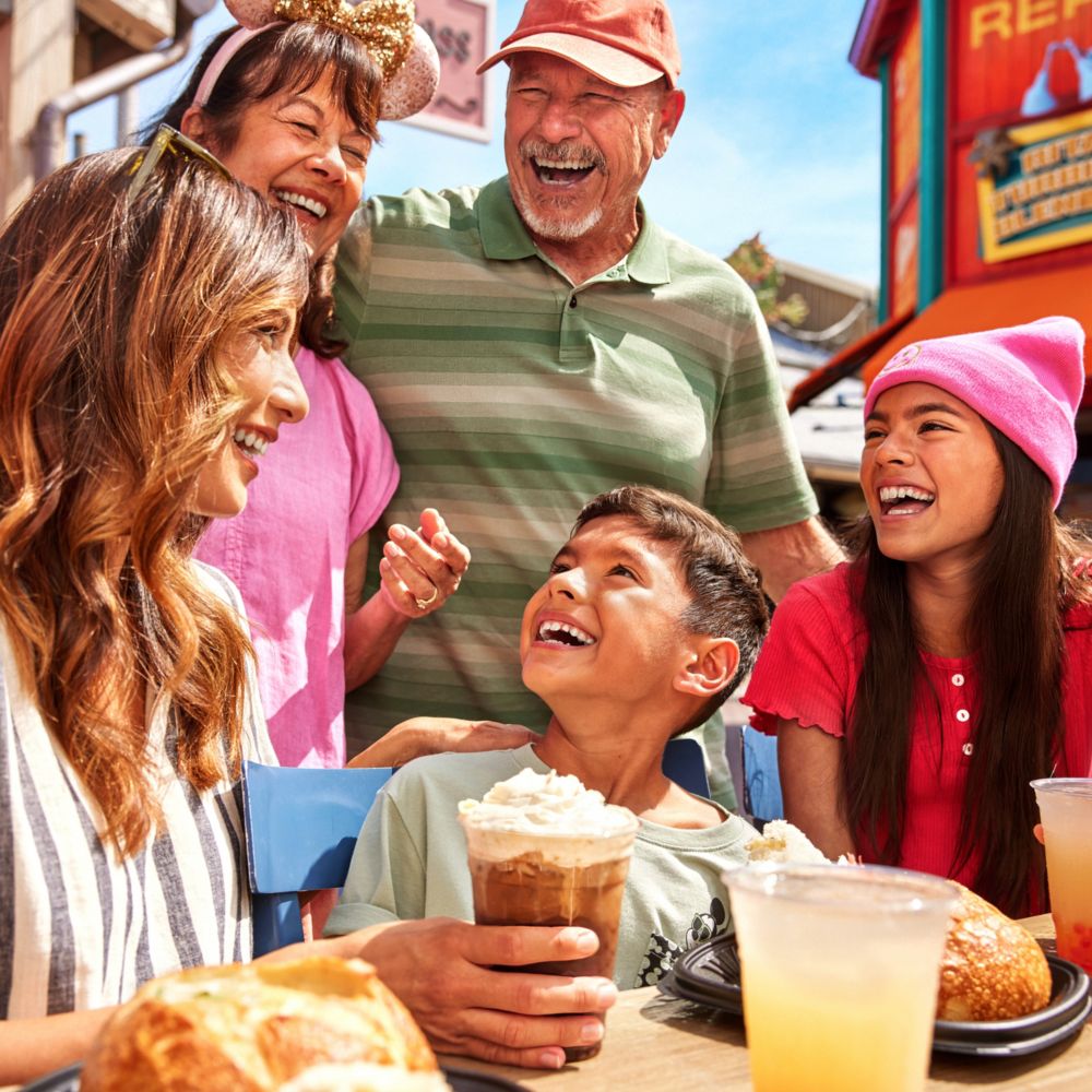Una familia de 6 personas disfrutando de bebidas y riendo en Paradise Gardens Park en Disneyland Resort