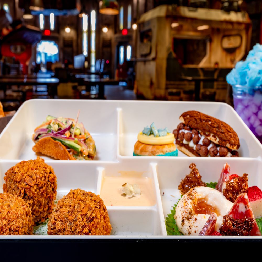 Paquete de comida A Nighttime Gathering, con bocados de croquetas fritas, salsa para untar, queso de cabra con chabacano, queso cheddar, queso Monterey Jack, totopos de pita, profiteroles, un taco y una bebida decorada con algodón de azúcar