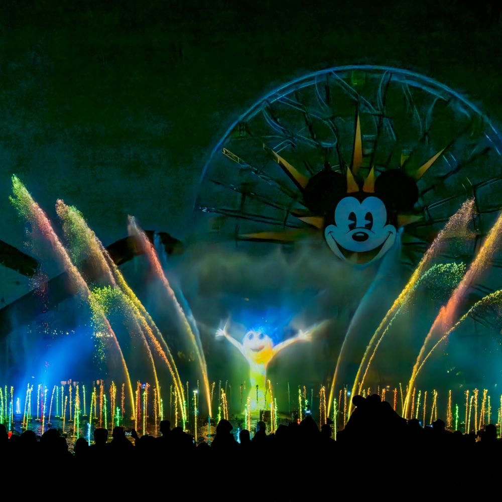 Joy de Inside Out iluminada en el rocío de las fuentes durante el espectáculo nocturno World of Color Happiness