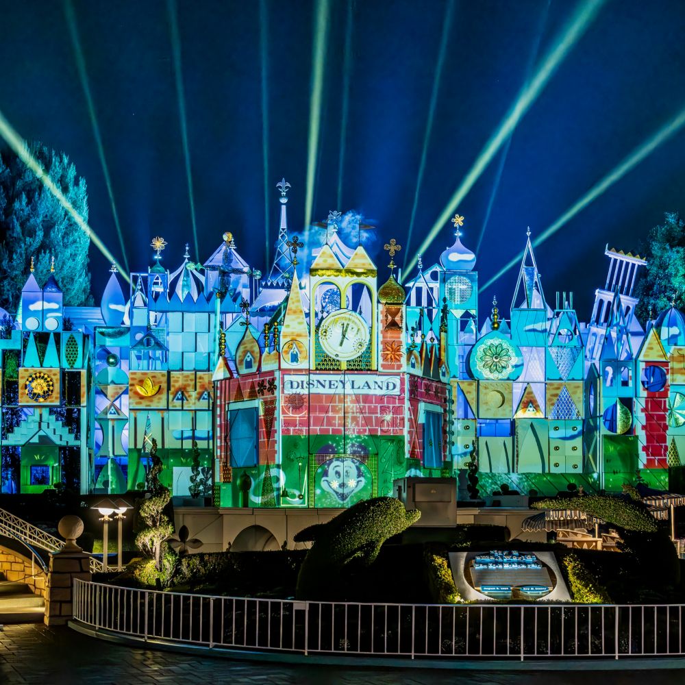 Vintage Disneyland imagery projected onto the façade of the it’s a small world attraction at night