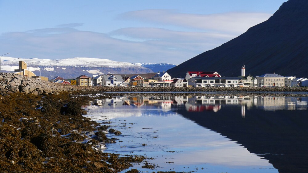 The waterside town of Invergordon, Isafjordour featuring an array    of buildings and a snowcapped mountain in the distance