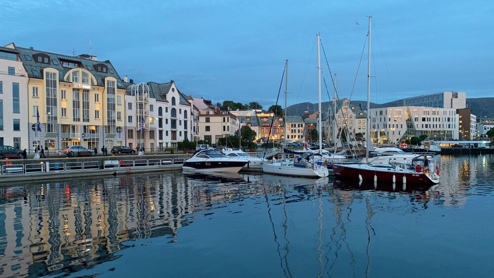 Sailboats and buildings reflecting in a quiet harbor at twilight