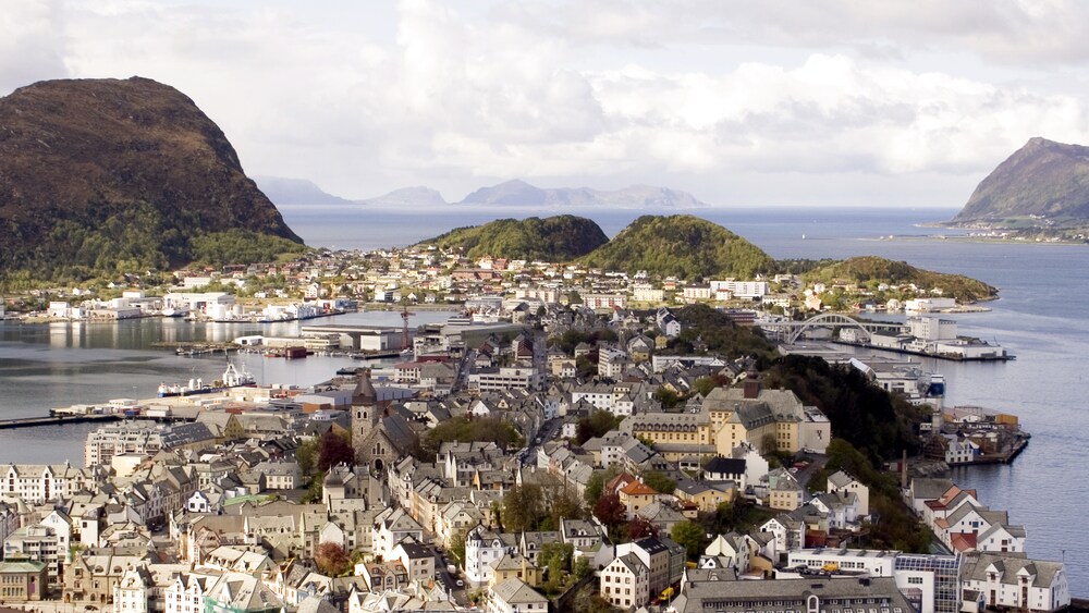 Alesund waterfront with historic buildings, a harbor, rolling green hills and distant mountains