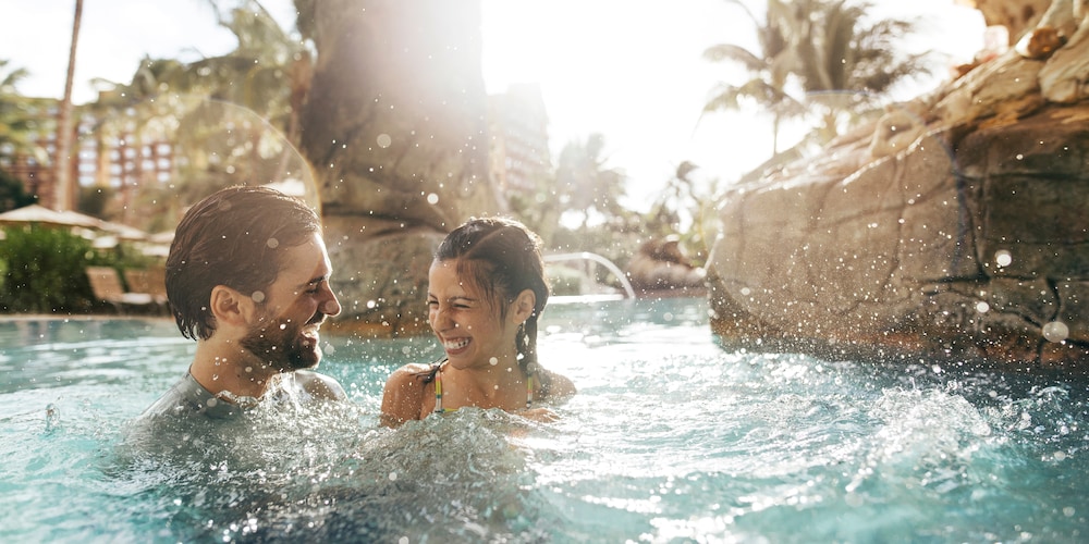 A father and daughter playing in an outdoor swimming pool at Aulani Resort