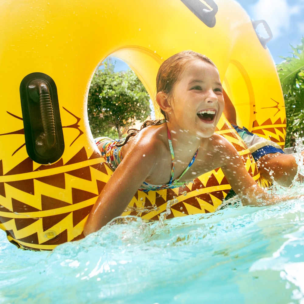 Two children playing in a lazy river with an inner tube