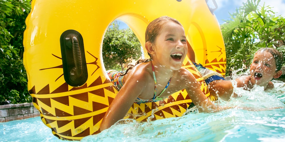 Two children playing in a lazy river with an inner tube