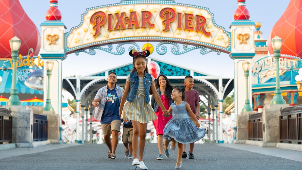 A family of six strolls under the Pixar Pier archway at Disney California Adventure Park