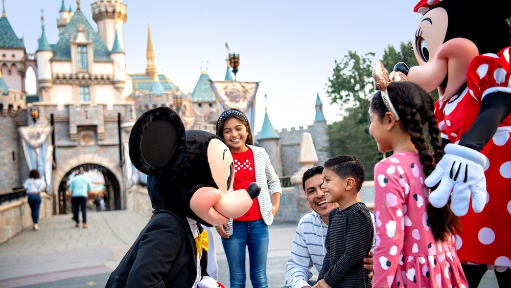 Mickey and Minnie Mouse greet a boy standing with his 2 sisters and his father