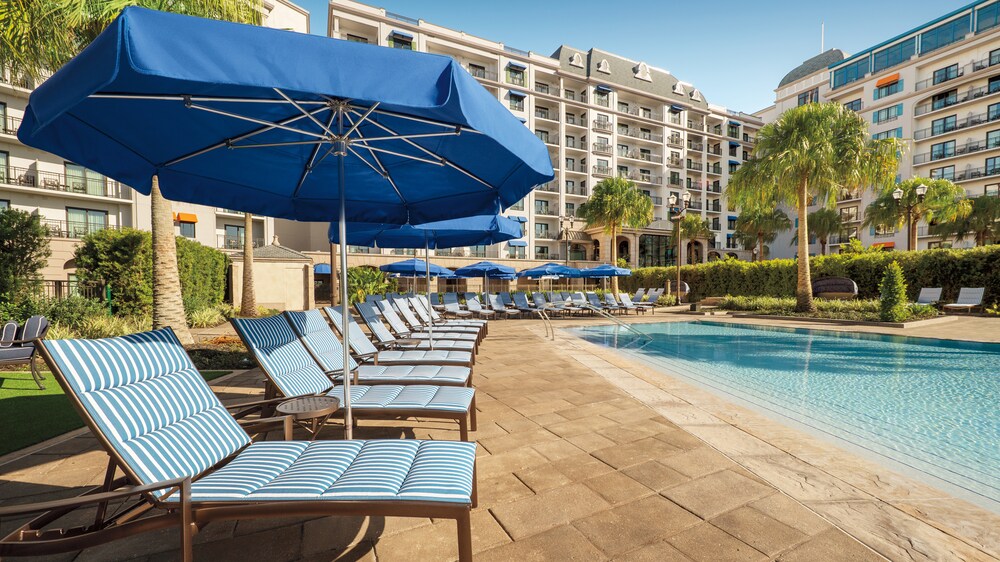 Several chaise lounge chairs and sun umbrellas surrounding Beau Soleil Pool at Disney's Riviera Resort