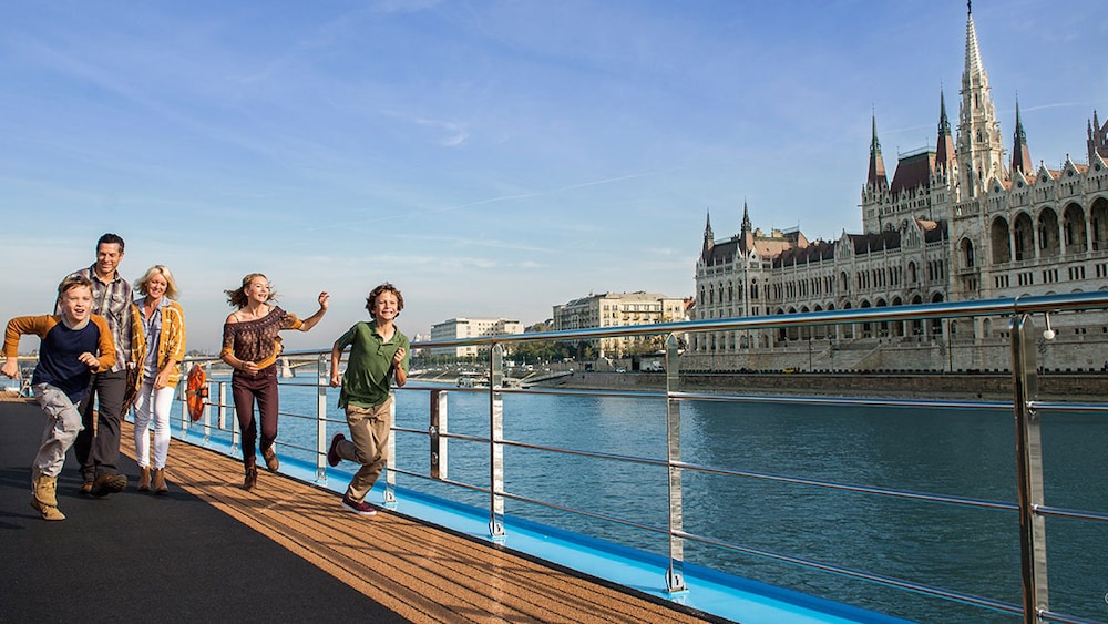 ブダペストのハンガリー国会議事堂の側をクルーズする船のデッキで散歩する家族