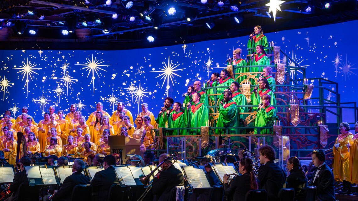 Singers in holiday-themed attire and an orchestra performing in the Candlelight Processional at Epcot