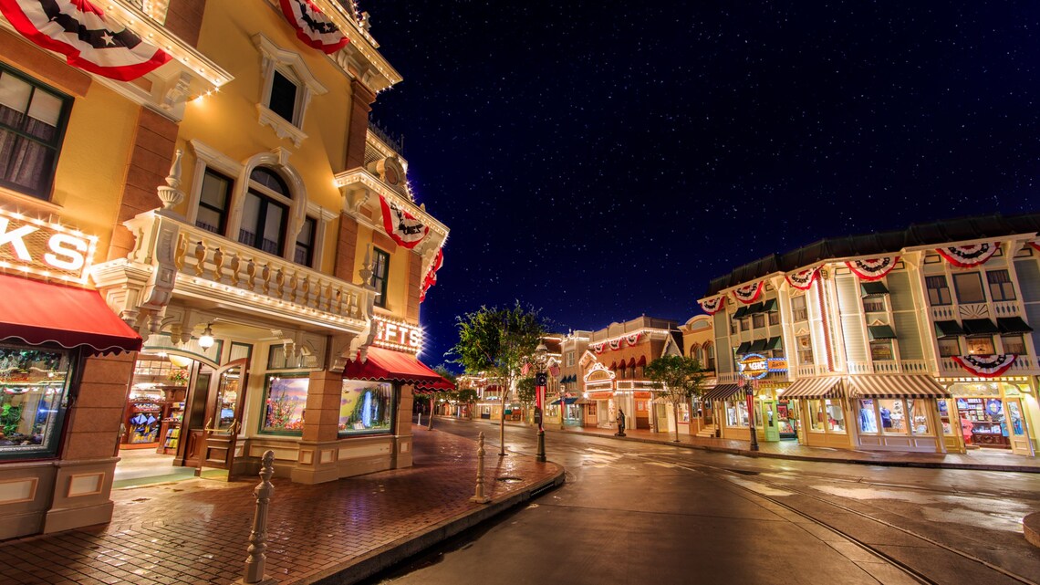 Nighttime view with storefronts illuminated on Main Street, U.S.A shopping district inside Disneyland Park in California