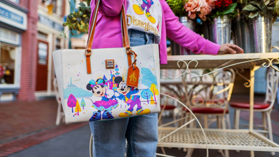 A girl in a Disneyland Resort T shirt holding a tote bag featuring Mickey Mouse and Minnie Mouse