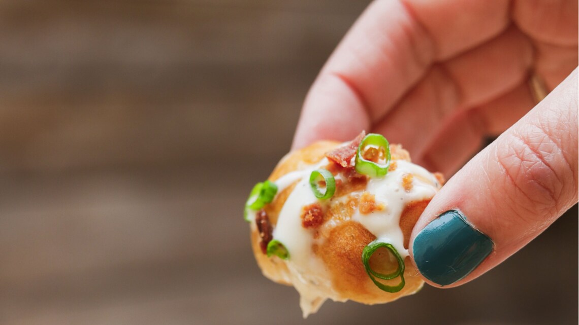 A woman picking up a piece from a plate stacked with bacon ranch bits