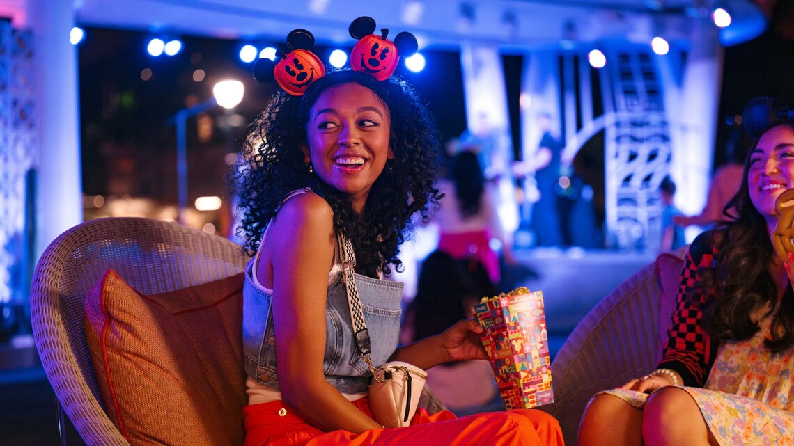 Two people sit outside eating popcorn at Downtown Disney District