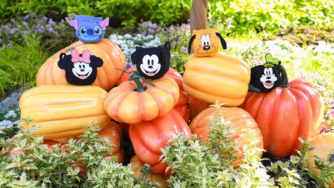 A stack of pumpkins topped with 5 bags featuring Minnie Mouse, Stitch, Mickey Mouse, Pluto and Goofy 