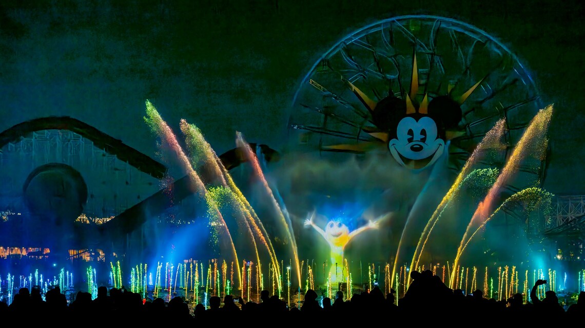 Joy de Inside Out iluminada en el rocío de las fuentes durante el espectáculo nocturno World of Color Happiness