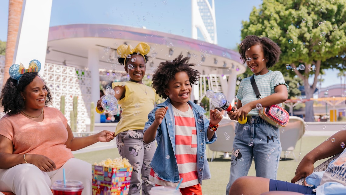 A mom and 3 children playing with Mickey Mouse bubble wands at Disney California Adventure