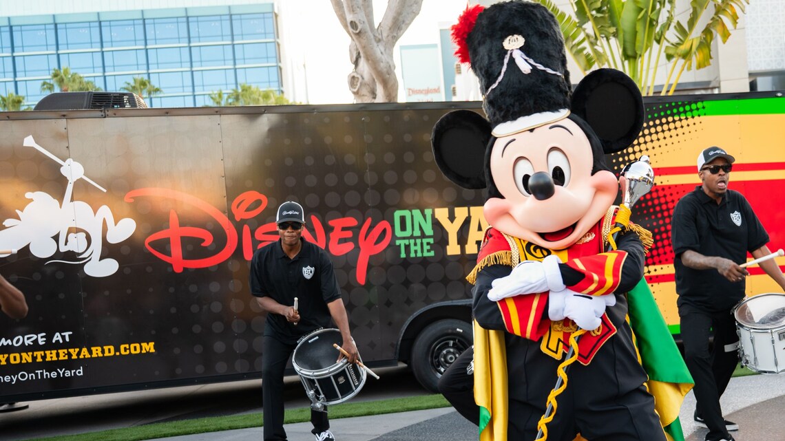 Mickey Mouse, dressed as a drum major, performs with a drumline in front of a Disney on the Yard bus at Disneyland Resort