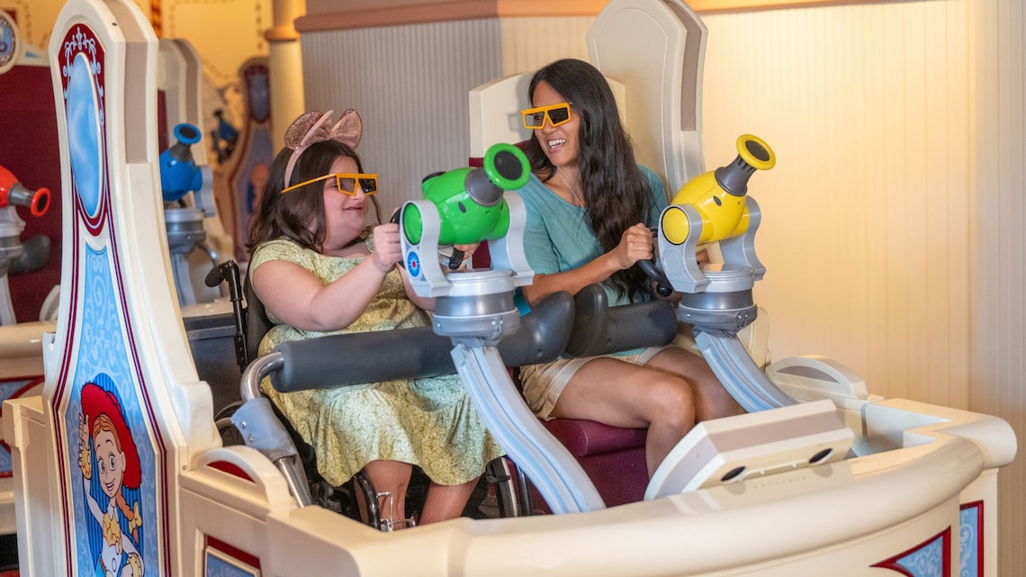 Dos Visitantes, uno en silla de ruedas, paseando en Toy Story Midway Mania