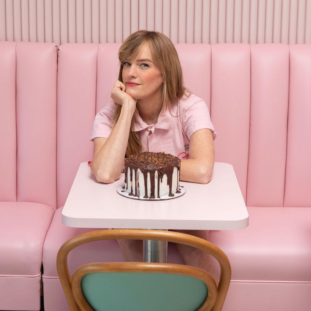 Erin McKenna sitting at a table with a cake